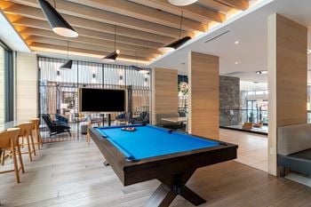 A pool table sits in the middle of a room with a tv on the wall